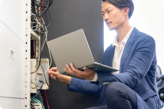 パソコンを片手にサーバーを確認するスタッフ